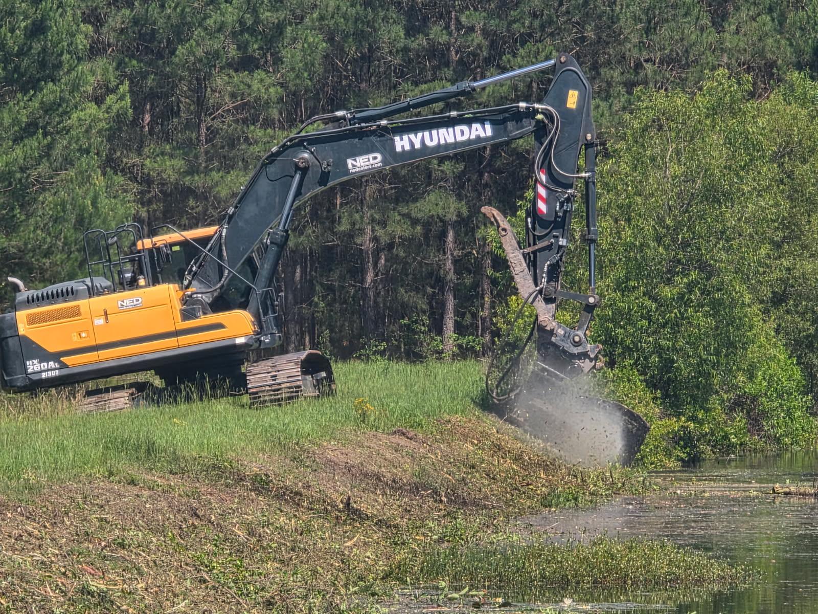 Pond Maintenance - Excavator with Mulching Attachment Truck hauling equipment for CRT Mulching Services.