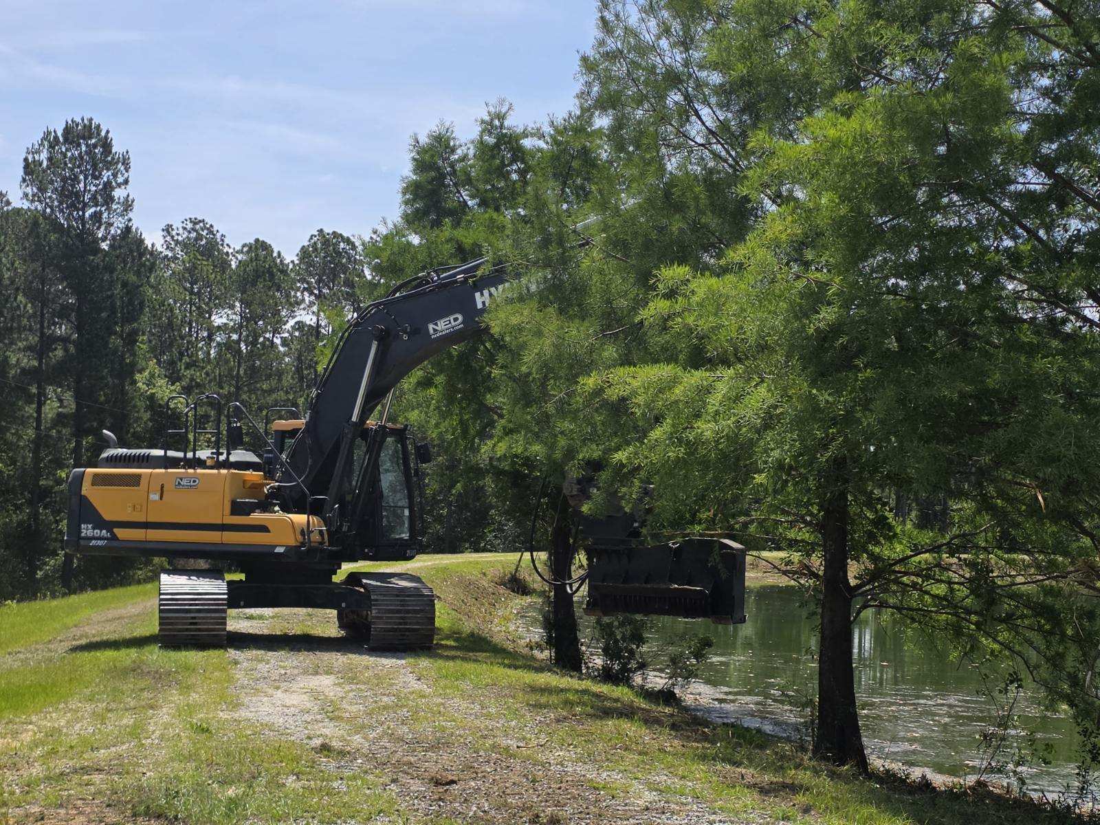 Pond Maintenance - Excavator with Mulching Attachment (2) Excavator with mulching attachment performing pond maintenance and vegetation clearing